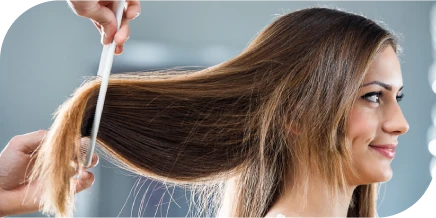 Hairstylist combing a woman’s long hair during a salon haircut