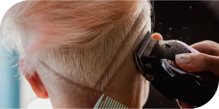 Stylist creating a clipper haircut design on short blonde hair