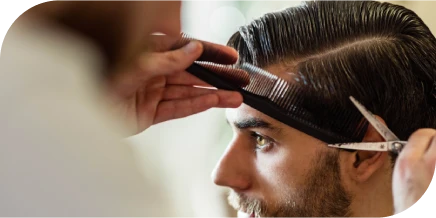 Stylist trimming a man’s hair with scissors and a comb during a precise haircut