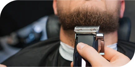 Barber trimming a client’s beard using professional clippers