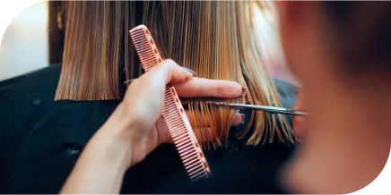 Cutting straight blonde hair with scissors and comb in a salon