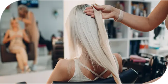 Hair stylist reviewing client’s blonde hair during a salon consultation