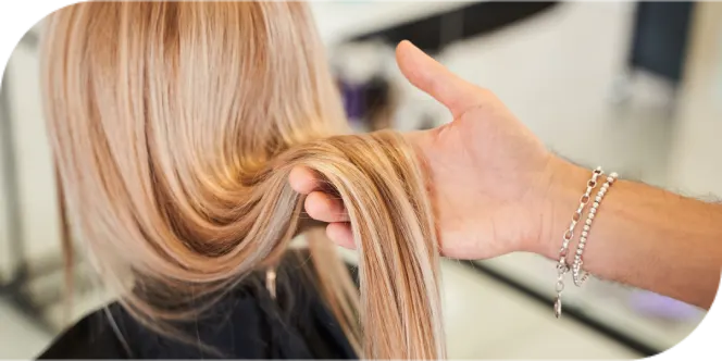 Salon professional inspecting healthy blonde hair for maintenance