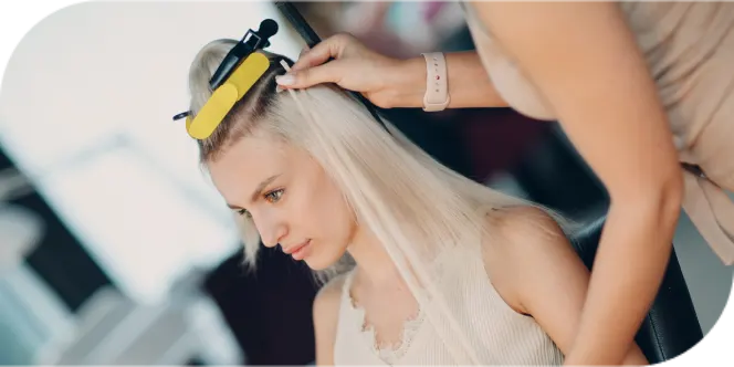 Professional stylist safely preparing blonde hair for extension application