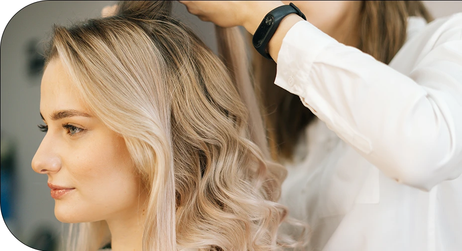 Hair stylist shaping loose blonde curls for a salon package service