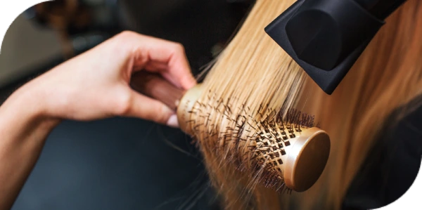 Professional blowout using round brush and dryer on long blonde hair