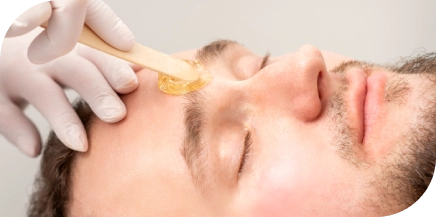 Man receiving eyebrow grooming with warm wax at salon