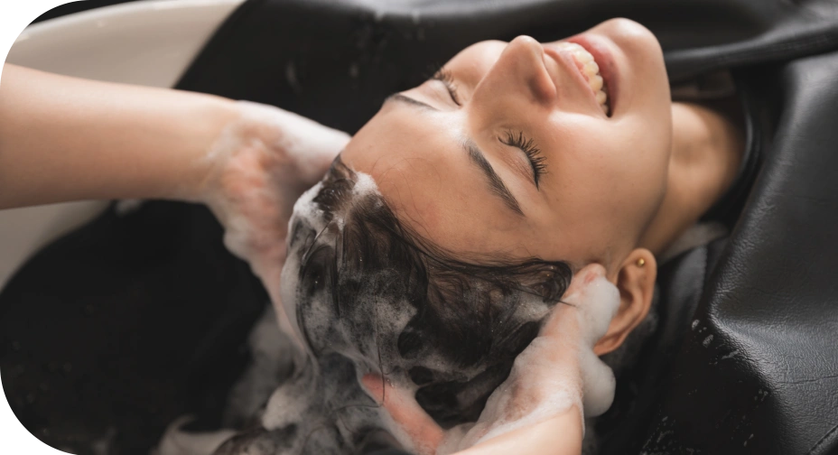 Woman smiling while receiving luxurious hair washing treatment