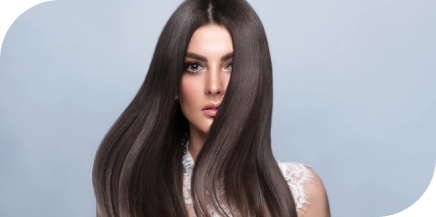 Woman with long, smooth, shiny dark hair posing against a light background