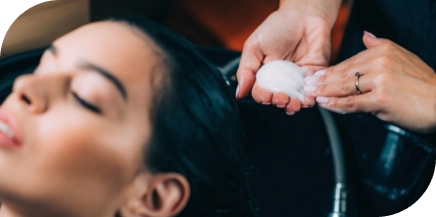 Professional applying deep conditioner to hair during salon treatment