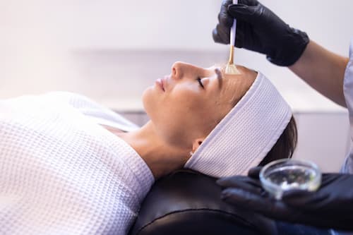 Facial treatment with esthetician applying skincare mask