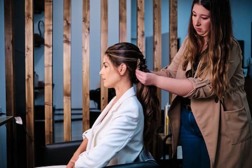 Professional hairstylist creating an elegant updo hairstyle in a salon