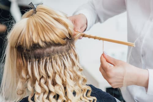 Applying perm rods to blonde hair during a professional perm treatment