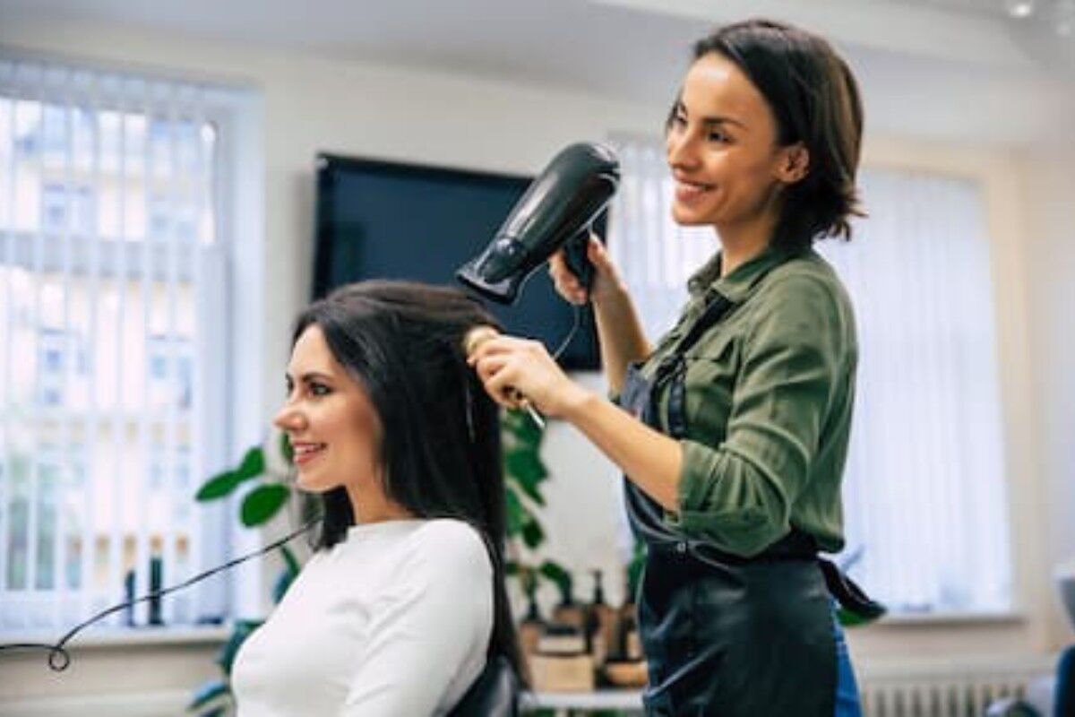 Hair stylist blow drying client's hair in salon package service