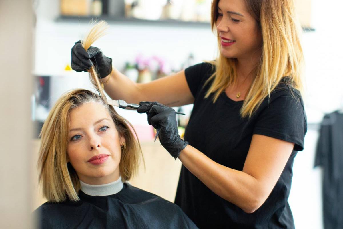 Professional hair treatment service in salon with stylist applying conditioner