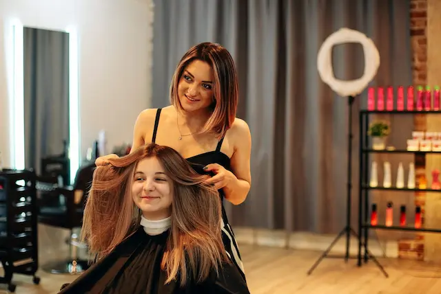 Stylist lifting and examining client’s hair before haircut or styling